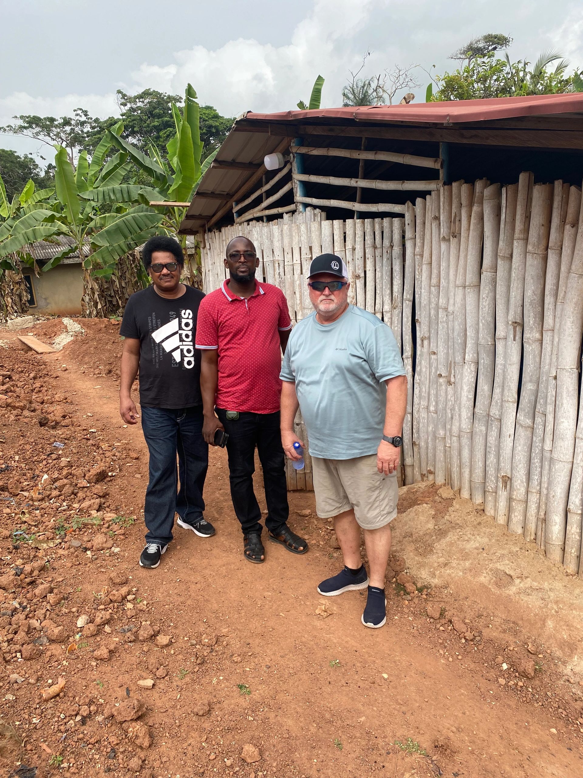 Mike Campbell standing with two national pastors at a building site in Ghana